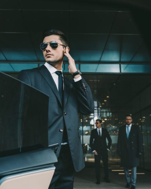 bodyguard-opening-car-door-for-businessman-and-listening-security-earpiece-e1631421593194-pczngmdv2v6fg4jhw9ff6gip9kmprsxvbxexbulrys
